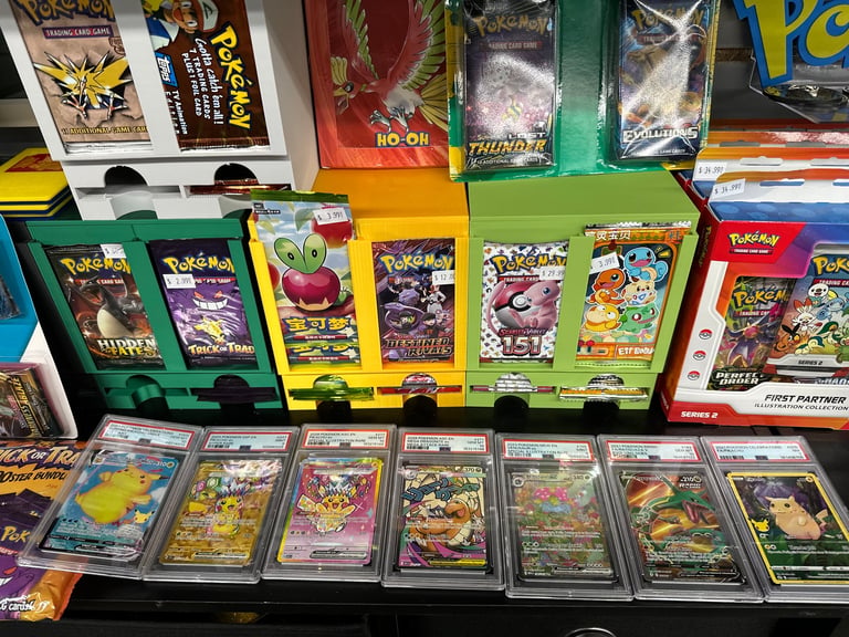 Pokemon trading card packs and graded cards displayed on retail shelf with colorful packaging boxes and individual sleeved cards