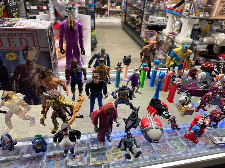 Collection of action figures and collectible toys displayed in a comic shop, featuring superhero and villain characters