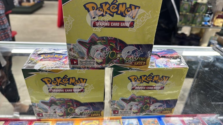 Three Pokémon Trading Card Game booster boxes displayed on a store shelf with other trading cards visible in background