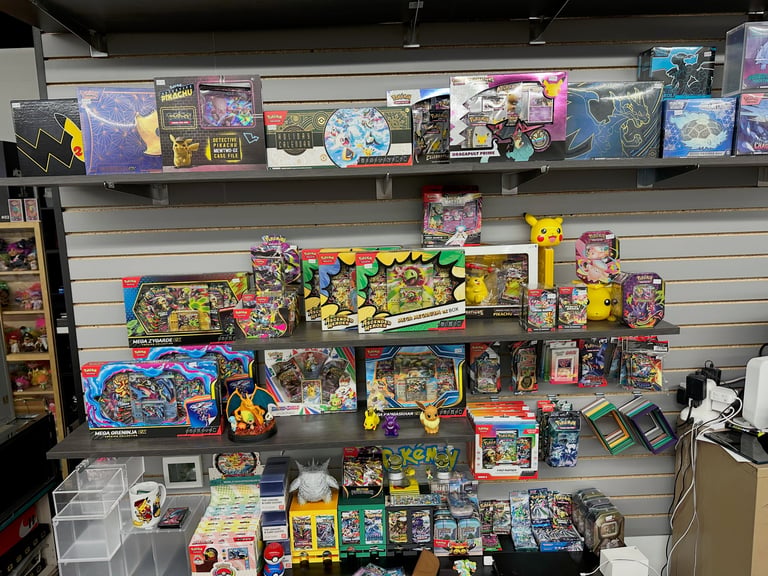 Retail shelf display of Pokemon merchandise and trading cards including collectible boxes, figurines, and games organized across multiple shelves