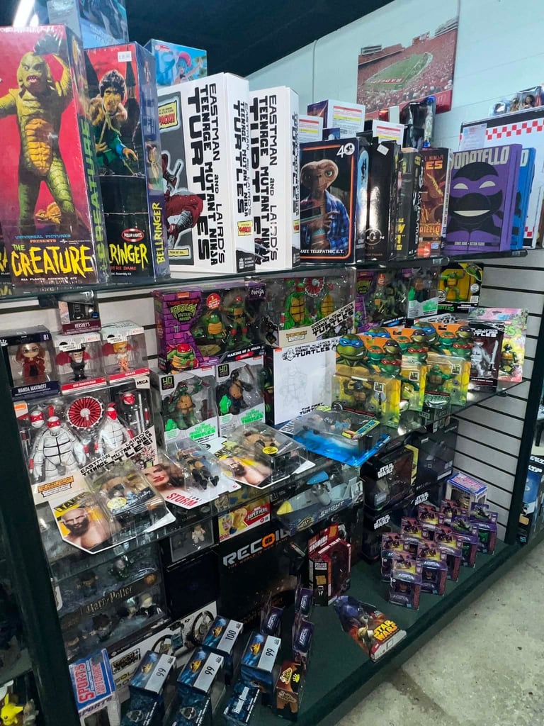Display case filled with collectible action figures, movie posters, trading cards, and vintage memorabilia merchandise