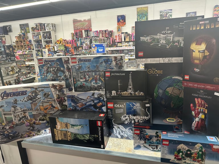 LEGO set display with multiple themed sets and posters on wall behind merchandise counter