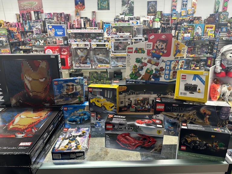 Cluttered collection display of action figures, collectible boxes, and memorabilia covering shelves and surfaces in a fan collection room