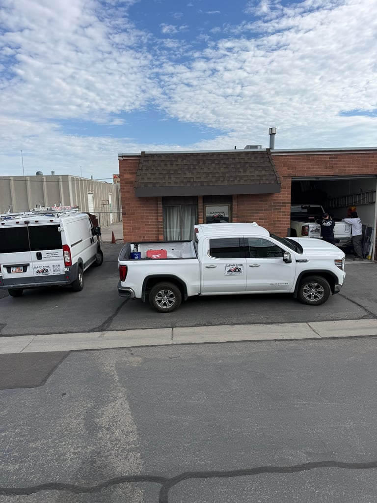 White pickup truck and van parked outside the Clean Edge Construction shop with garage