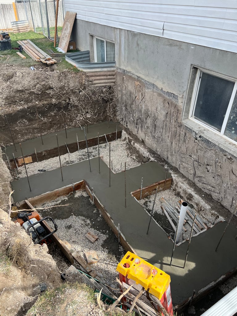 Basement foundation excavation with concrete footings poured and rebar bracing in progress