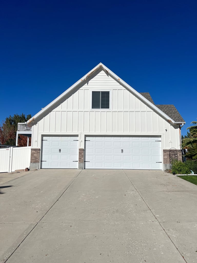 White detached garage with fresh exterior trim and a neat driveway