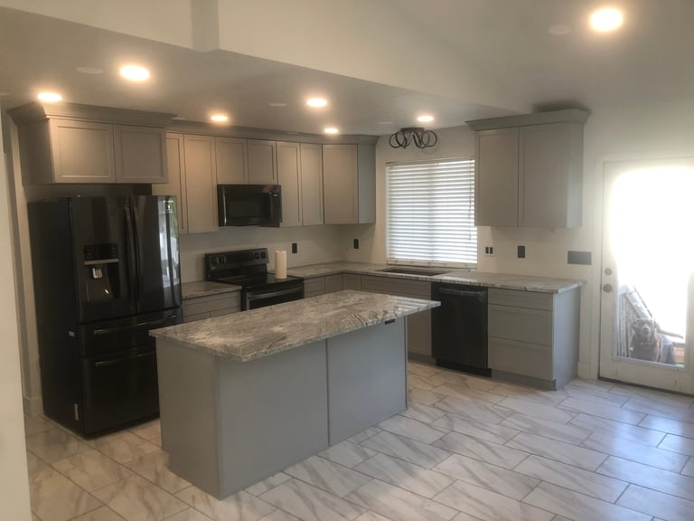 Modern kitchen with gray cabinetry, granite island and black appliances