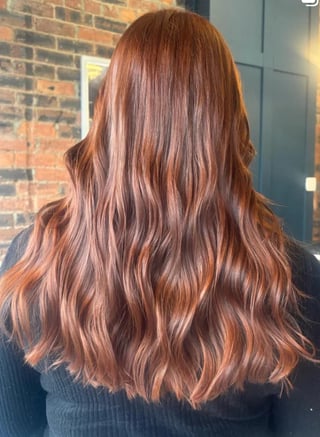 Back view of woman with long wavy copper-brown hair with highlights