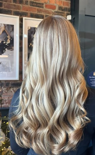 Back view of a woman with long, wavy blonde and caramel highlighted hair
