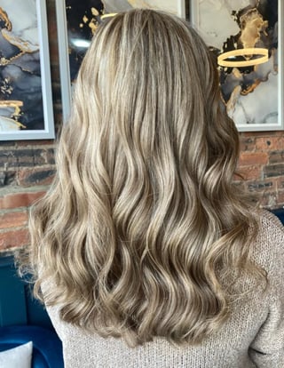 Back view of woman with long wavy blonde and gray hair styled with soft waves