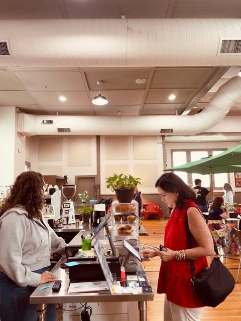 Indoor market with vendor booth and customers browsing merchandise