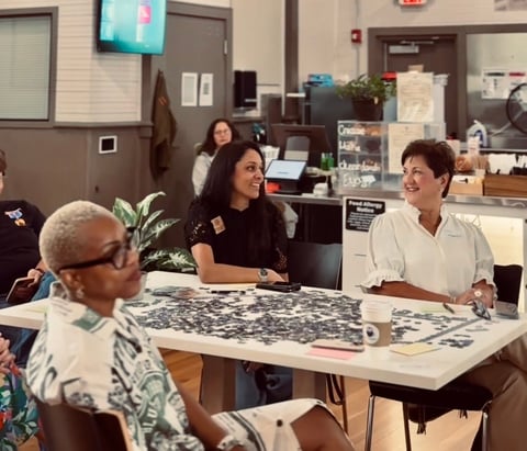Three women sitting at a table during a community gathering at Café Floralia