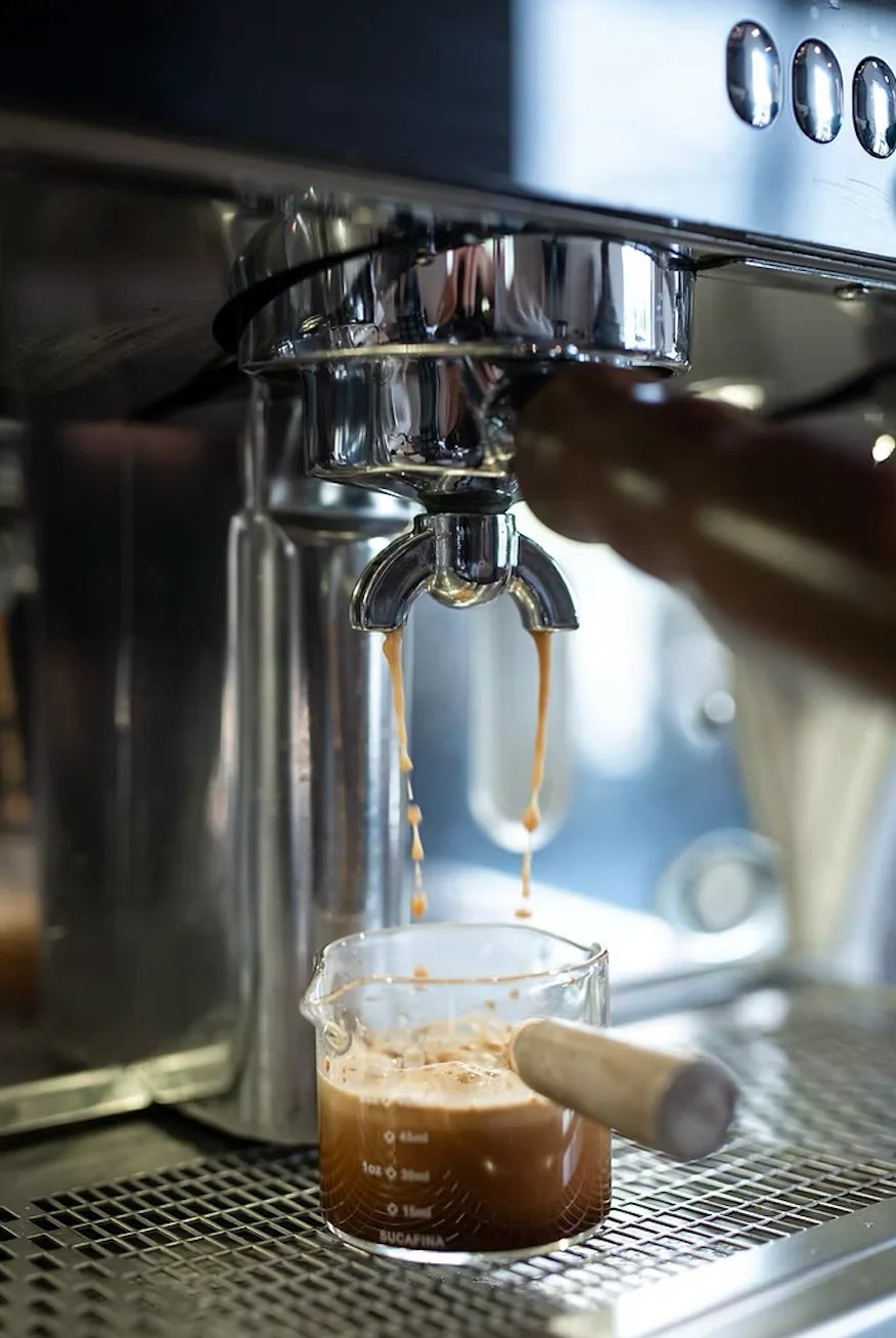 Espresso machine dispensing dark coffee into a small glass cup — fresh specialty coffee at your event