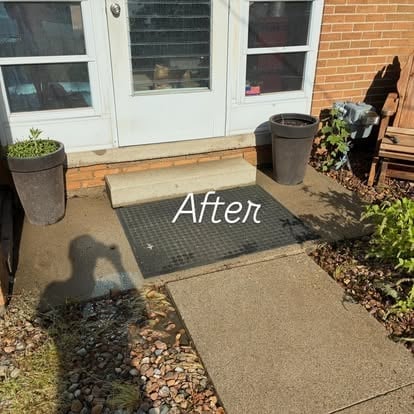 After photo of entryway with new black rubber mat placed on concrete pathway leading to white doors with brick building backdrop