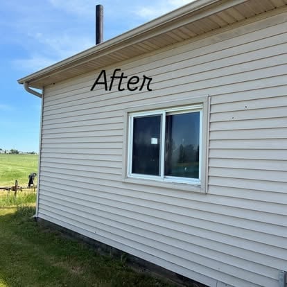 After: Exterior of a white mobile home after renovation, featuring new siding and window against a green lawn