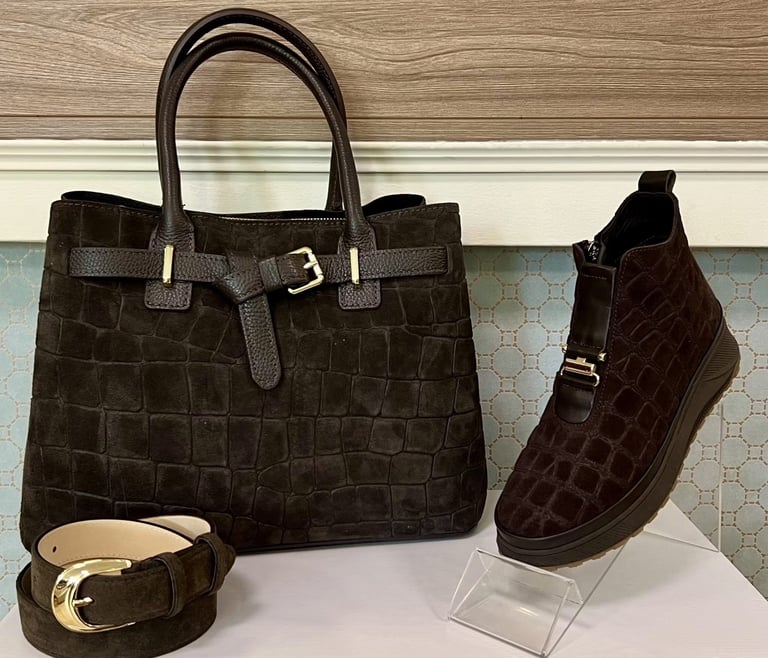 Black crocodile-textured leather handbag, matching ankle boot, and gold-buckle belt displayed on white surface