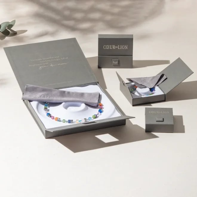 Luxury jewelry brand packaging with gray boxes displaying beaded bracelets wrapped in tissue paper