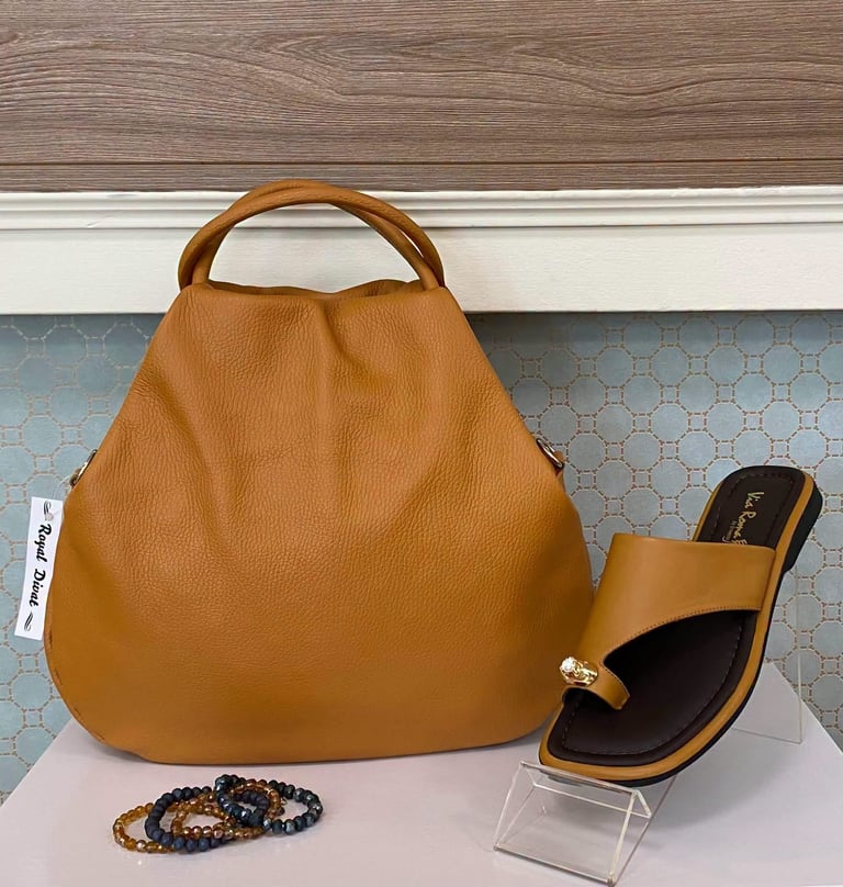 Tan leather hobo bag displayed with matching sandal and beaded bracelets on a light surface