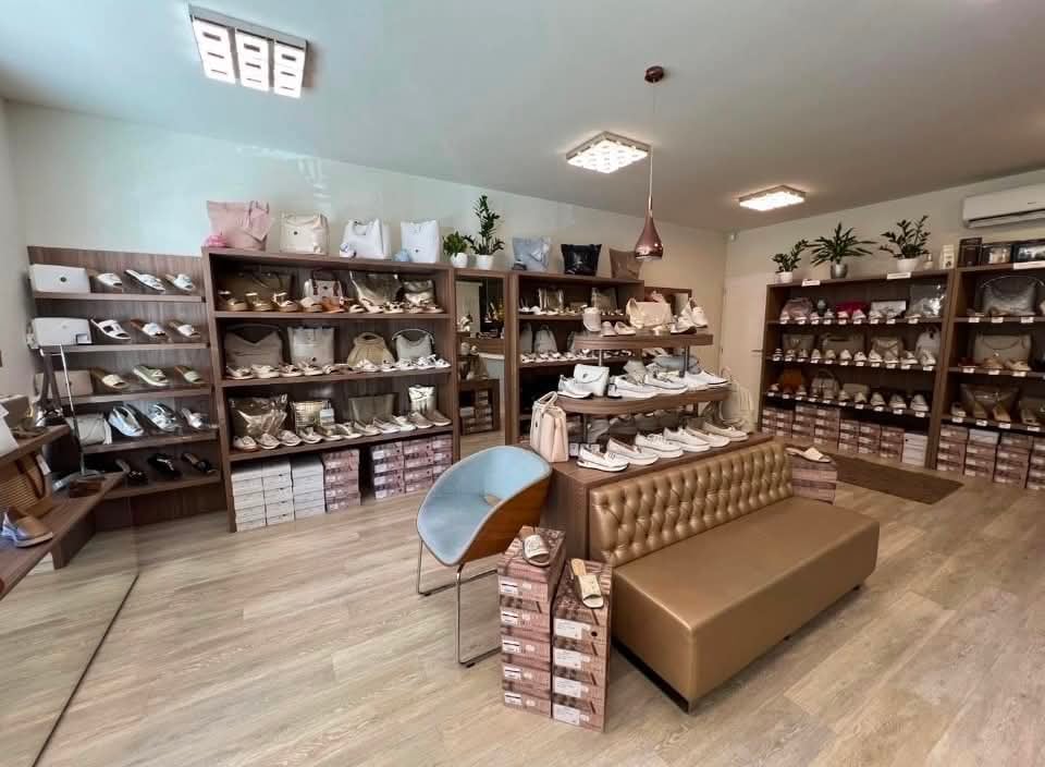 Bright retail store interior with wooden shelves displaying merchandise, a tan upholstered seating bench, and display items on wooden flooring.