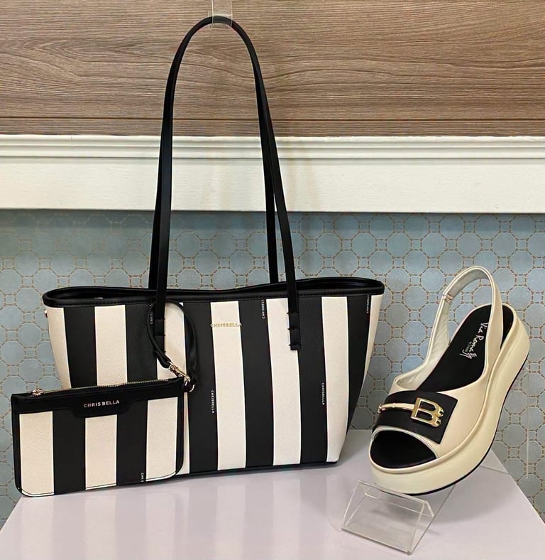 Black and white striped tote bag with matching wallet and cream and black platform loafer shoe displayed on stand