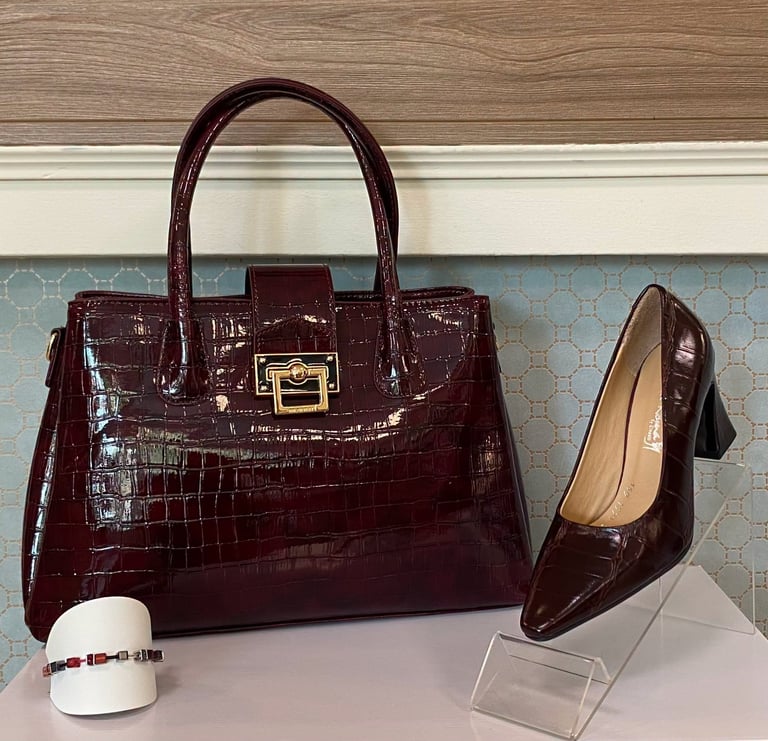 Burgundy crocodile-embossed handbag with matching patent leather heel pump and small accessories on display