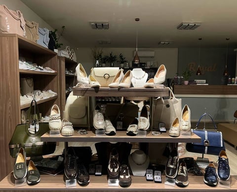 Retail shoe store display with shelving units showing various footwear styles in beige and black