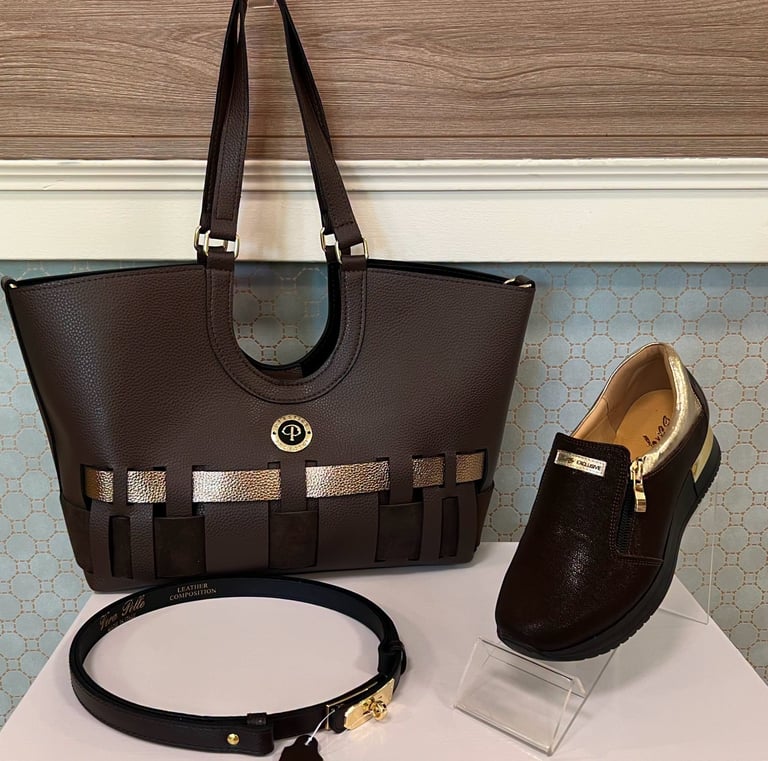 Brown leather tote bag with stripe detail displayed with matching black loafer shoe and thin black belt
