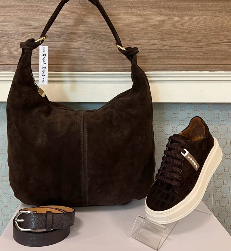Brown suede hobo bag with matching leather belt and dark suede sneaker with white sole displayed together