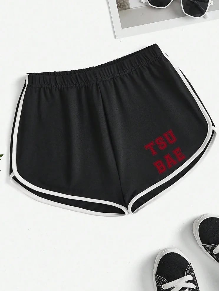Black athletic shorts with white trim and red TSU Bae text displayed on white background with sunglasses and sneakers