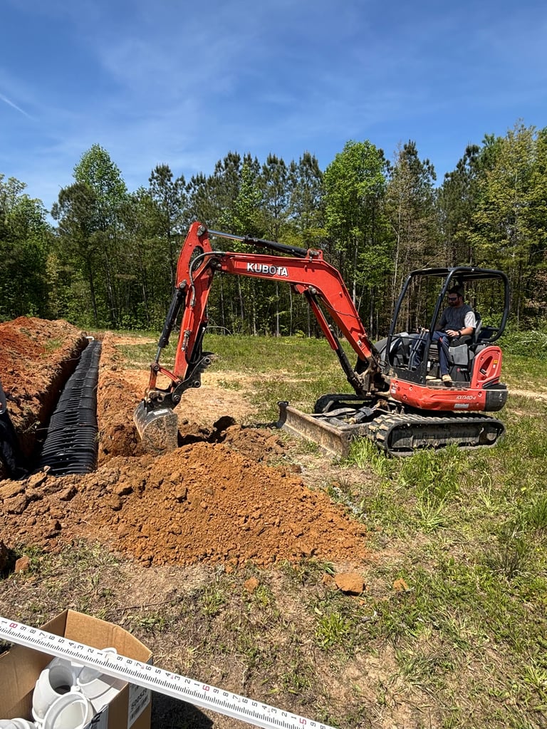 Red Kubota mini excavator working beside a septic system installation