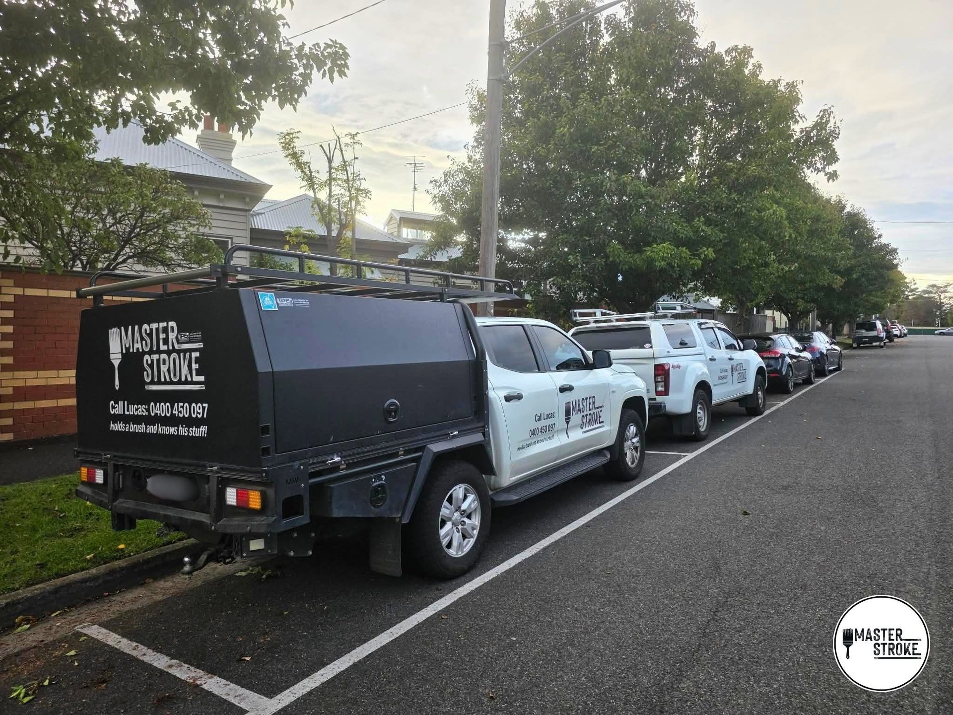 Row of service vans parked along a residential street, with a black Master Stroke van in front and white utility vehicles behind