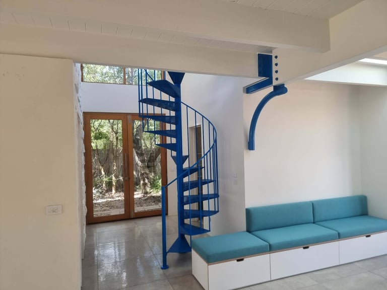 Modern interior with spiral staircase, turquoise seating, and glass doors overlooking greenery