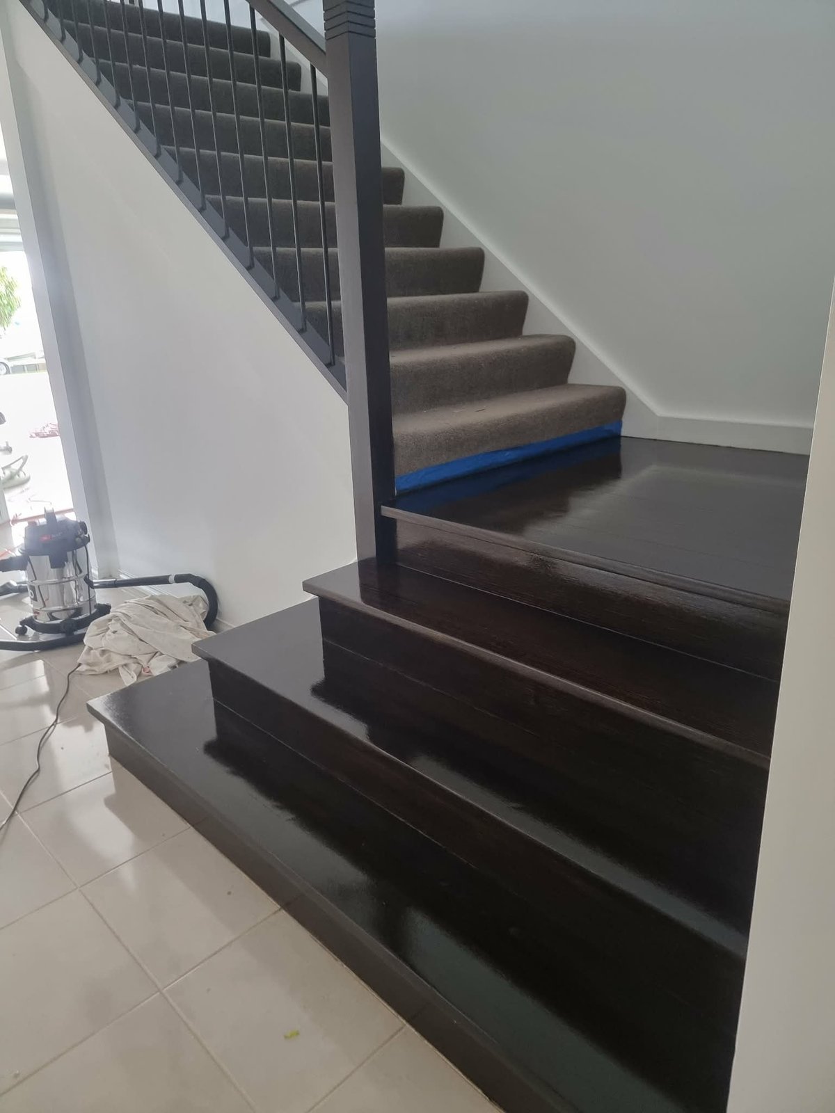 Modern staircase with dark steps, metal railing, and white walls in a bright interior space.