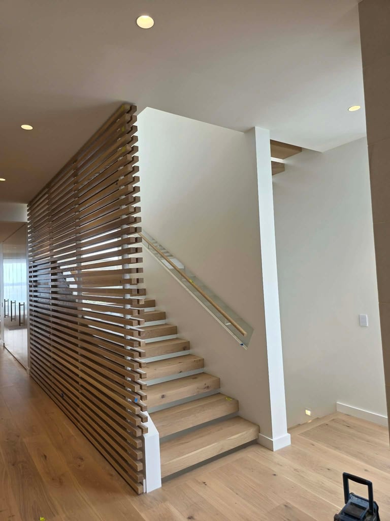 Modern wooden staircase with horizontal slat railing in contemporary home interior with light wood flooring