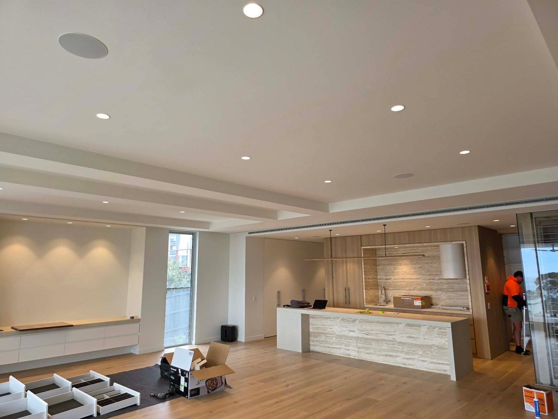 Modern office interior with reception desk, whiteboard wall, recessed lighting, and wooden flooring under construction