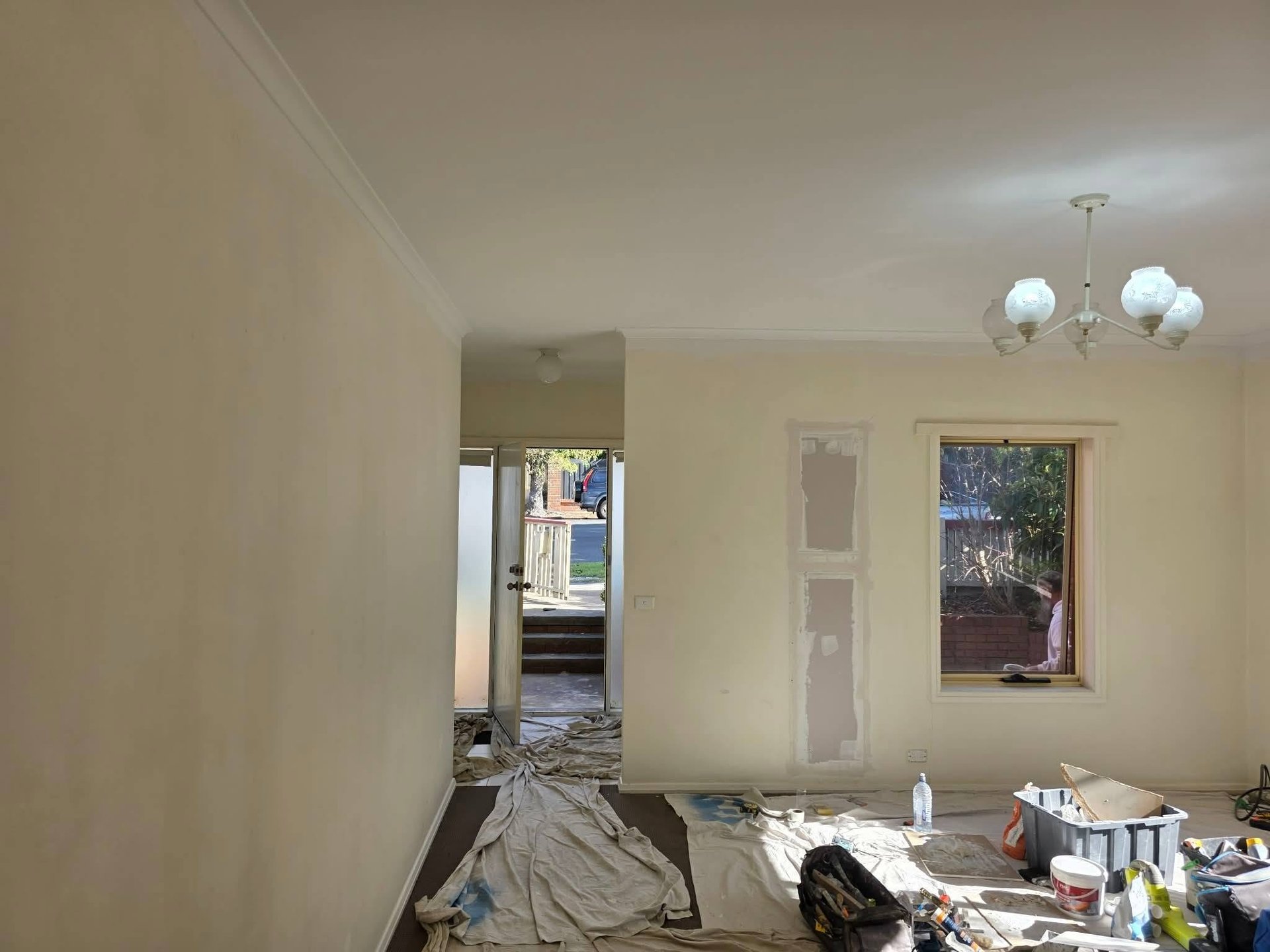 Unfinished interior room with cream-colored walls, mirrors, doorway, and scattered construction materials on the floor