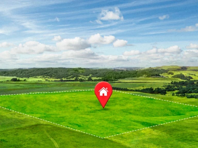 Red location pin with house icon centered on green aerial view of rural land with property boundary lines