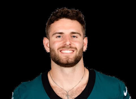 Portrait of a smiling man wearing a teal and black athletic jersey against a black background