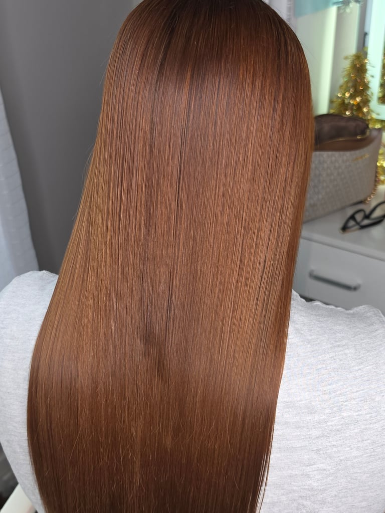 Back view of person with long, straight copper-brown hair, wearing white shirt indoors