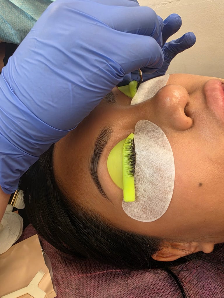 Beautician applying false eyelashes to a clients eye using tweezers during a lash extension procedure