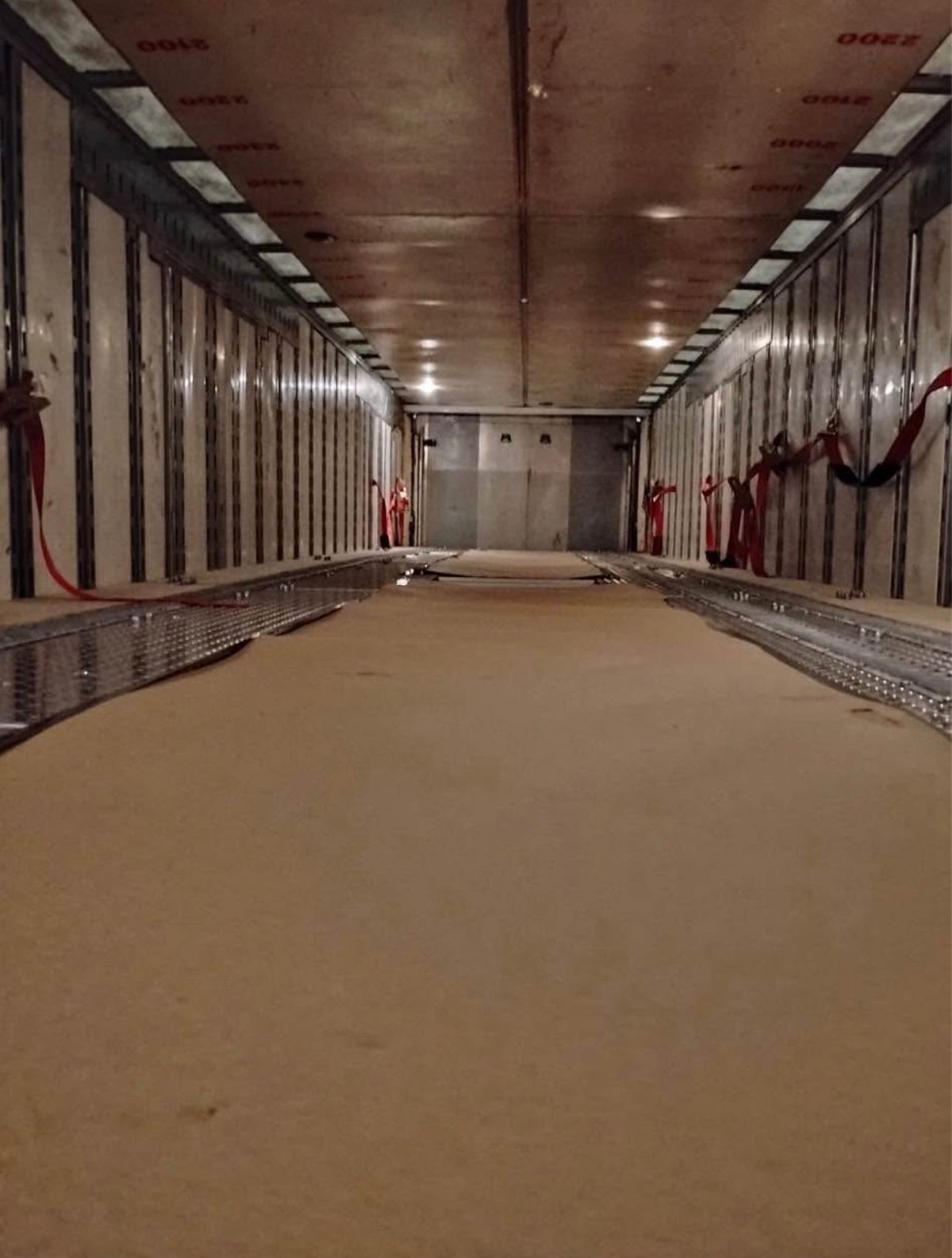 Interior of empty enclosed cargo trailer with metal walls and overhead lights