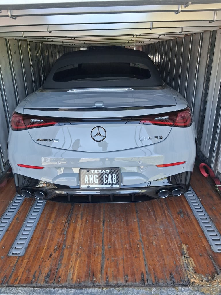 White Mercedes-Benz EQS sedan loaded in the back of a metal cargo container or truck bed