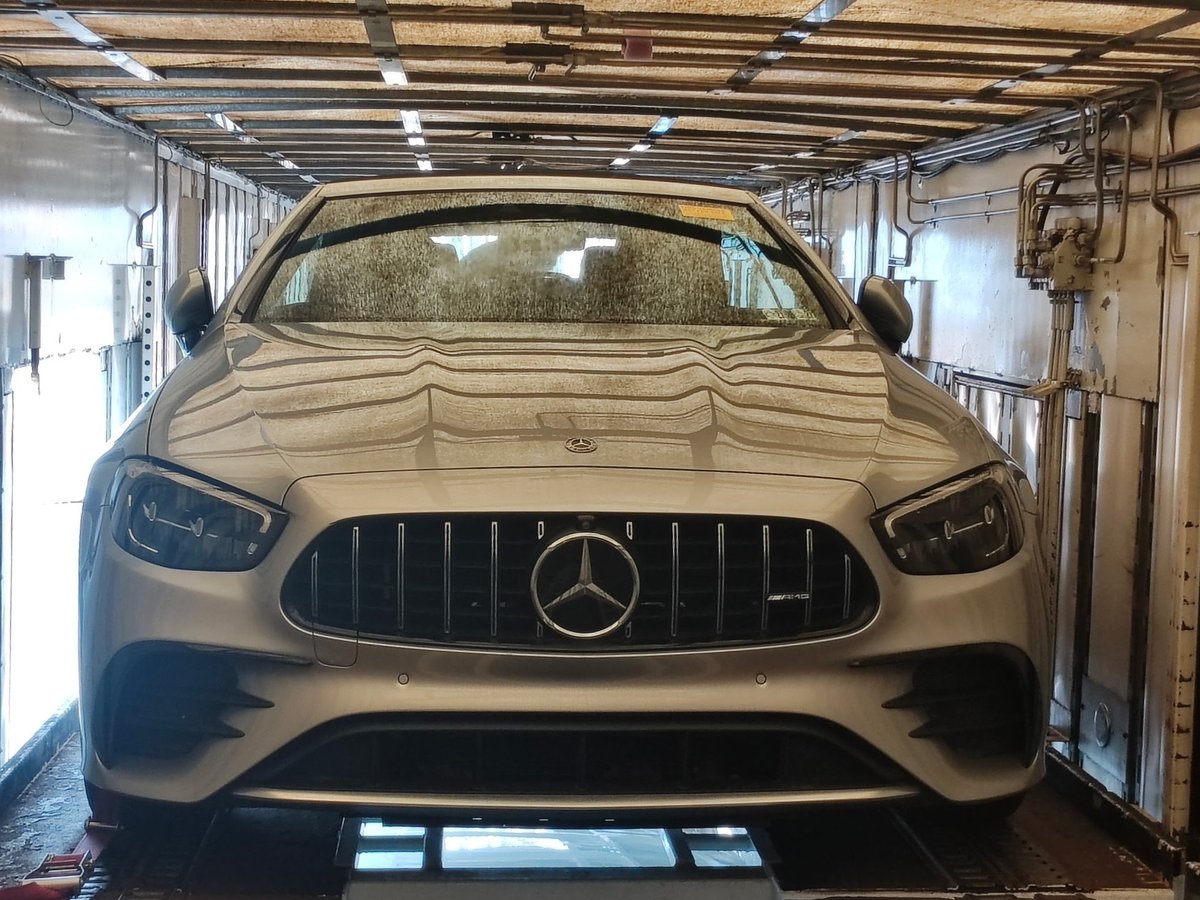 White Mercedes-AMG vehicle front view in a garage with industrial lighting and concrete floor