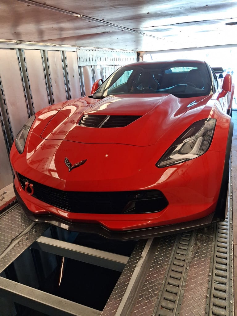 Bright red Corvette sports car in a parking garage with white wall markers and metal floor