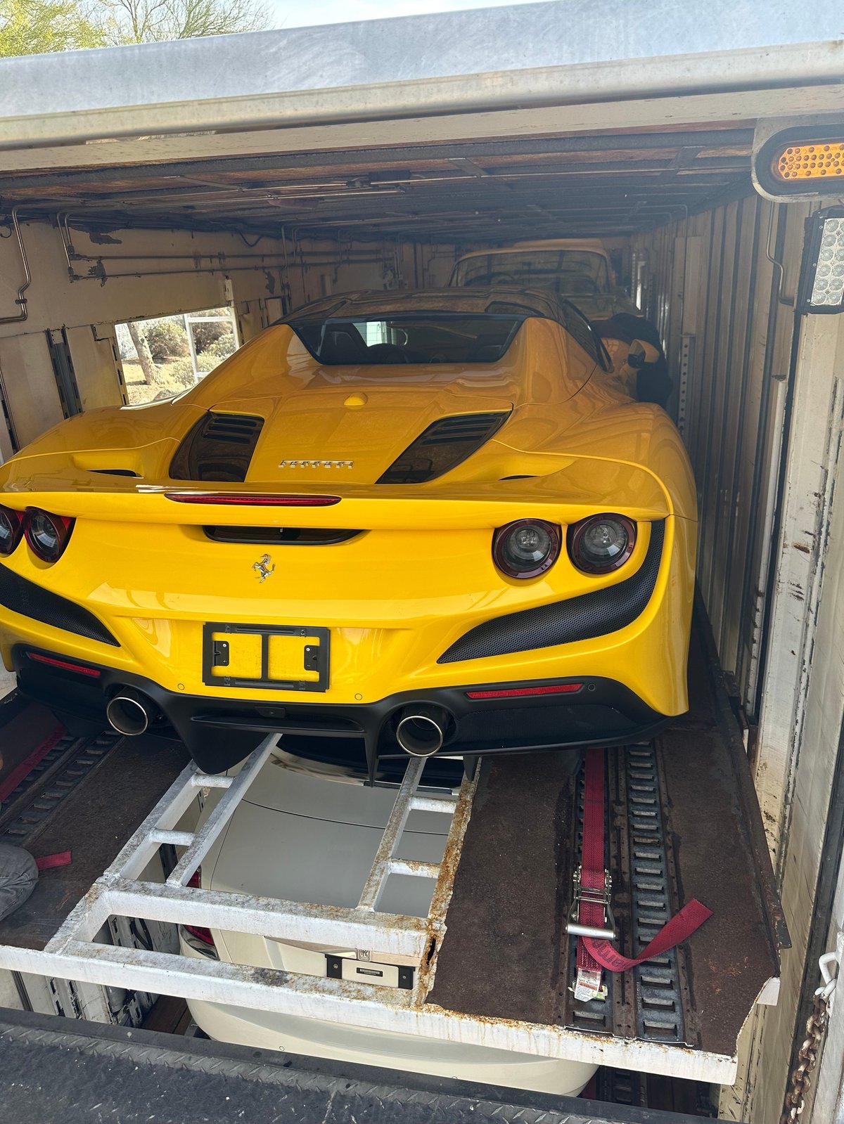 Yellow Ferrari sports car loaded on enclosed transport hauler viewed from inside the trailer
