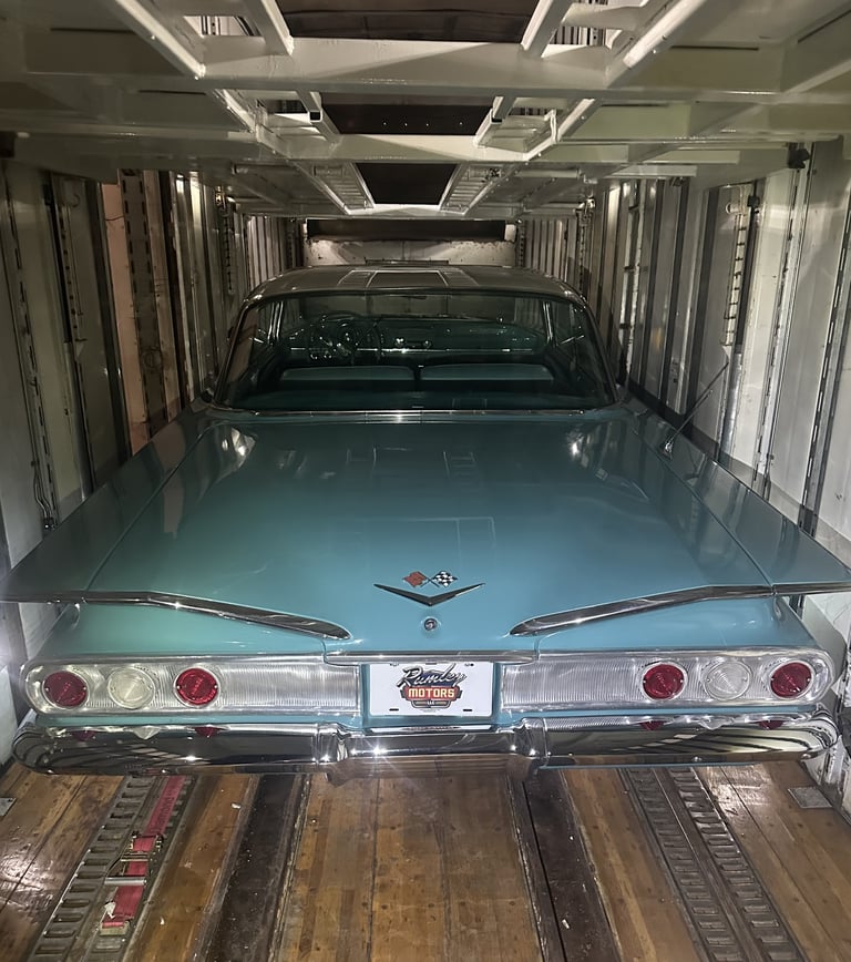 Turquoise classic car with chrome trim loaded in an enclosed automotive transport trailer