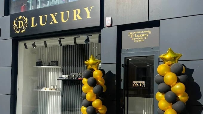Luxury storefront with gold and black balloon decorations flanking the entrance and gold signage above