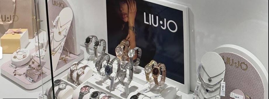 A retail jewelry display featuring LIU JO branded items with multiple rings and accessories arranged on white display stands