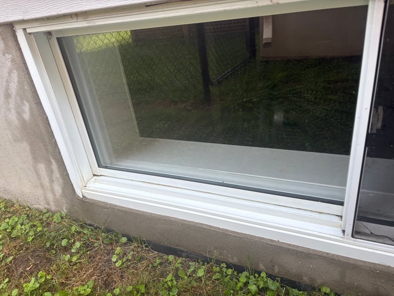White framed basement window after cleaning, glass clear and frame wiped clean