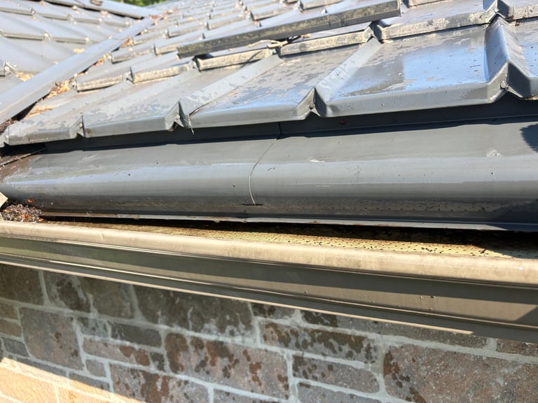 Cleaned roof gutter cleared of debris, draining freely against brick wall
